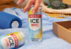 Promotional image of Smirnoff Ice can as a hand goes to lift a can off a blanket and another can lies on its side.