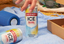 Promotional image of Smirnoff Ice can as a hand goes to lift a can off a blanket and another can lies on its side.