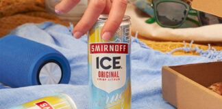 Promotional image of Smirnoff Ice can as a hand goes to lift a can off a blanket and another can lies on its side.