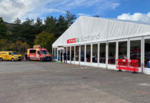 Image of the front of the Spar Scotland trade show tent with vans parked outside.