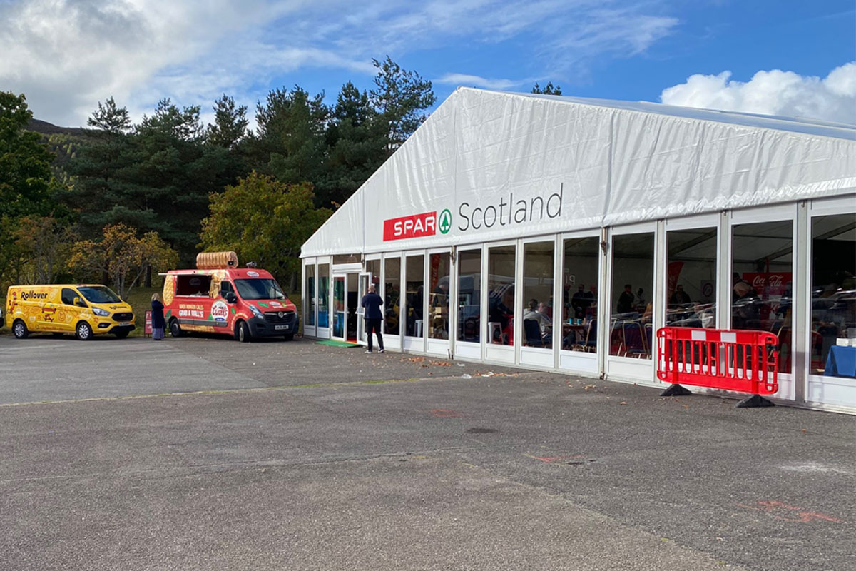 Image of the front of the Spar Scotland trade show tent with vans parked outside.