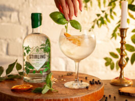 Stirling Distillery rolls into Co-op stores A bottle of Stirling Distillery's Classic Gin stands next to a glass with a drink serve as a hand places some basil into the drink.