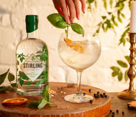 Stirling Distillery rolls into Co-op stores A bottle of Stirling Distillery's Classic Gin stands next to a glass with a drink serve as a hand places some basil into the drink.