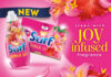 Promotional image of the Surf laundry detergent rebrand, with pack shots of the products against a pink background that has flowers. The text reads 'clean with joy infused fragrance'.