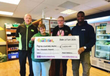 An Asda Foundation staff member presents The Courtyard Pantry Foodbank with a cheque for £1,000.