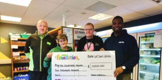 An Asda Foundation staff member presents The Courtyard Pantry Foodbank with a cheque for £1,000.