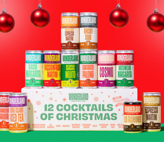 Enjoy winter with Wonderland with new Christmas cocktails pack A pack of Wonderland Cocktails 12 Cocktails of Christmas stands on a green table with the 12 cans stacked around the pack against a red background and red baubles hanging from the ceiling.