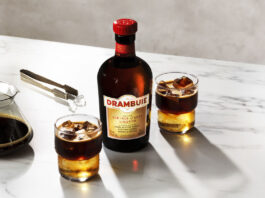 A bottle of Drambuie with two Drambuie Iced Espresso serves stand next to the bottle on a countertop.