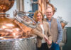 Paul and Tiffany Kerruish, co-founders of Fynoderee Distillery stand next to a still in a warehouse.