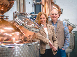 Fynoderee auctions off rare bottle for RNLI Paul and Tiffany Kerruish, co-founders of Fynoderee Distillery stand next to a still in a warehouse.