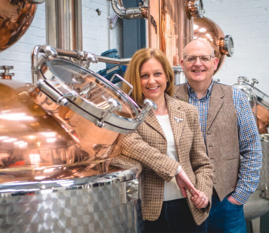 Fynoderee auctions off rare bottle for RNLI Paul and Tiffany Kerruish, co-founders of Fynoderee Distillery stand next to a still in a warehouse.