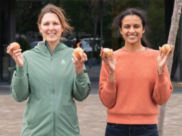 HUID aims to peel back plastic with onion packaging Two people stand holding onions in front of a building.