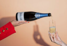 A person pours of a bottle of Hambledon sparkling wine into a glass which a person is holding.