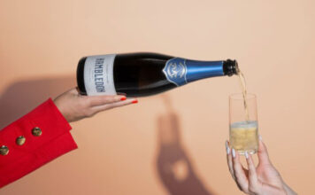 A person pours of a bottle of Hambledon sparkling wine into a glass which a person is holding.