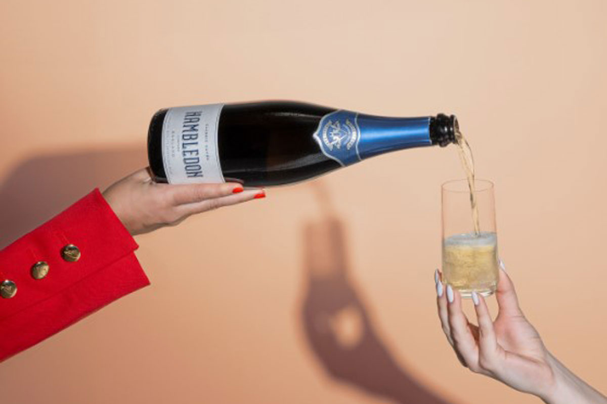 A person pours of a bottle of Hambledon sparkling wine into a glass which a person is holding.