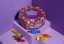 Promotional image of Quality Street paper tubs featuring the tub and sweets from the tub against a purple background.