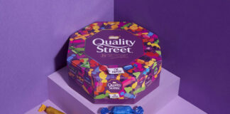 Promotional image of Quality Street paper tubs featuring the tub and sweets from the tub against a purple background.