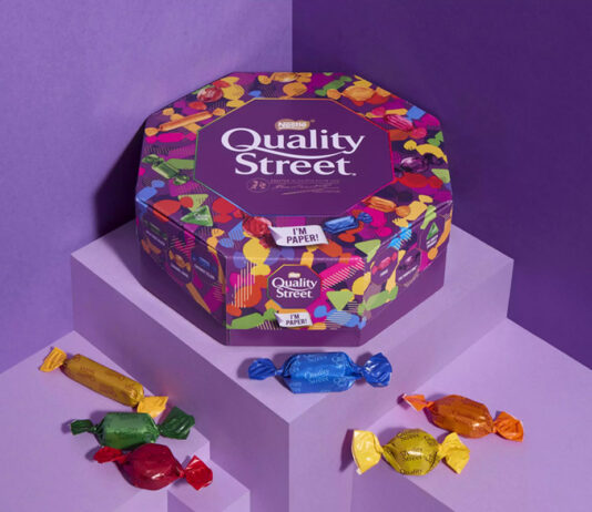 Nestlé trials paper Quality Street tubs Promotional image of Quality Street paper tubs featuring the tub and sweets from the tub against a purple background.