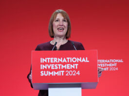 Chancellor confirms rise in worker wages Chancellor of the exchequer Rachel Reeves stands at a podium with the text "International Investment Summit 2024" against a red backdrop.