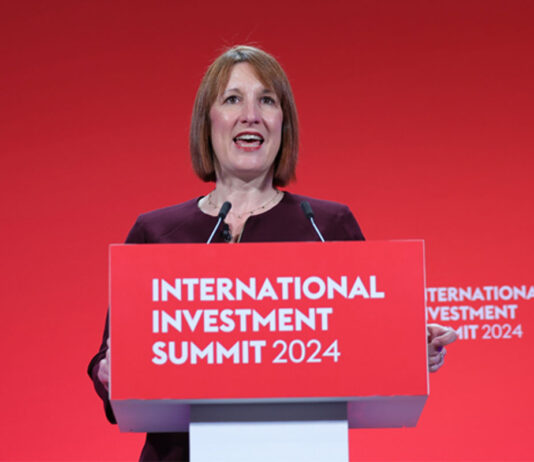 Chancellor confirms rise in worker wages Chancellor of the exchequer Rachel Reeves stands at a podium with the text "International Investment Summit 2024" against a red backdrop.