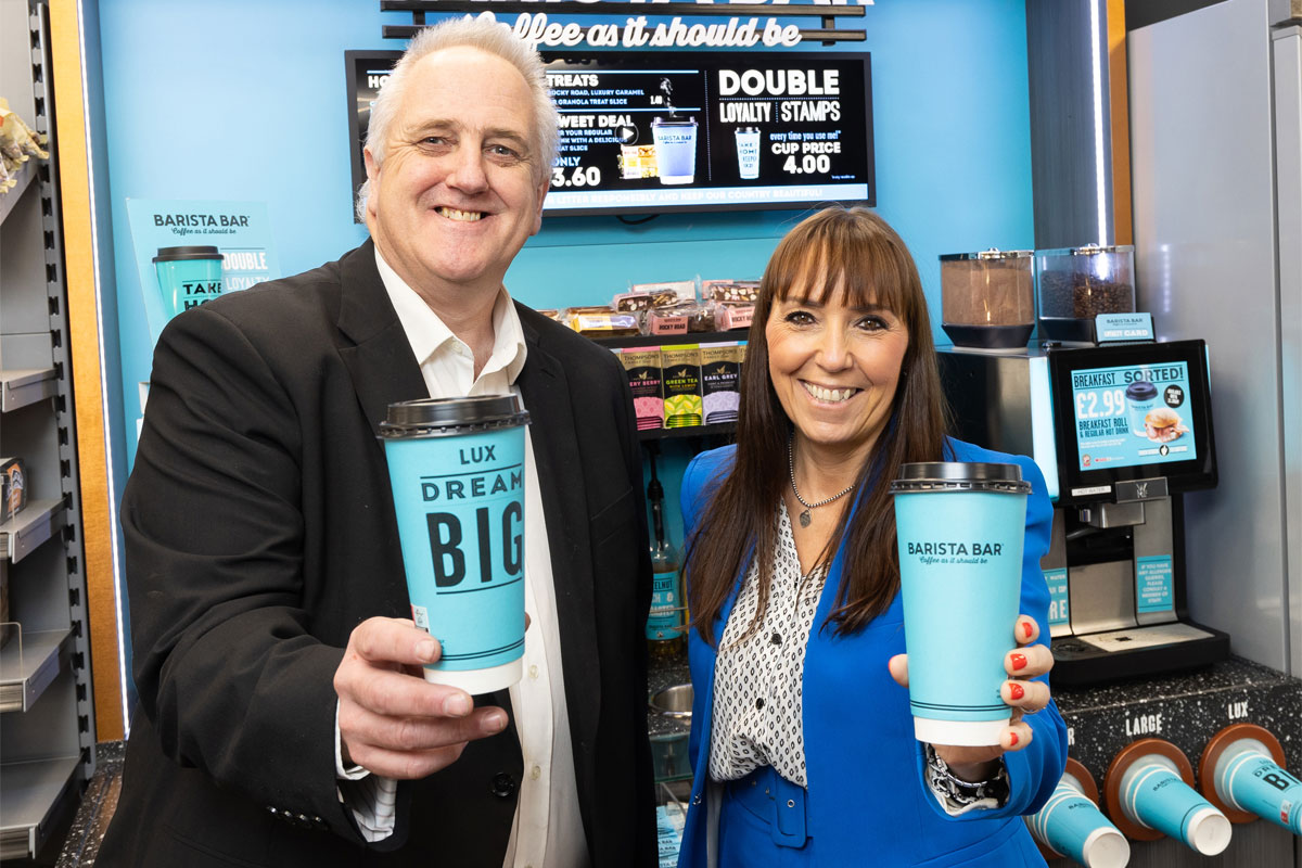 Stephen Brown, head of food to go at CJ Lang & Son, and Keavy O'Mahony-Truesdale, brand manager at Barista Bar, stand in front of a Barista Bar machine holding Lux branded cups from the service.