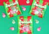 Packets of Swizzels Squashies Naughty & Nice sit against a red and green backdrop with the sweets scattered across the table.