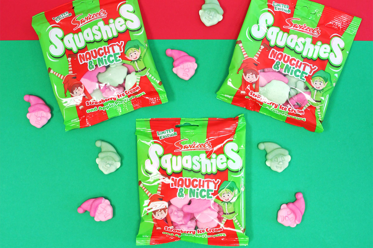 Packets of Swizzels Squashies Naughty & Nice sit against a red and green backdrop with the sweets scattered across the table.