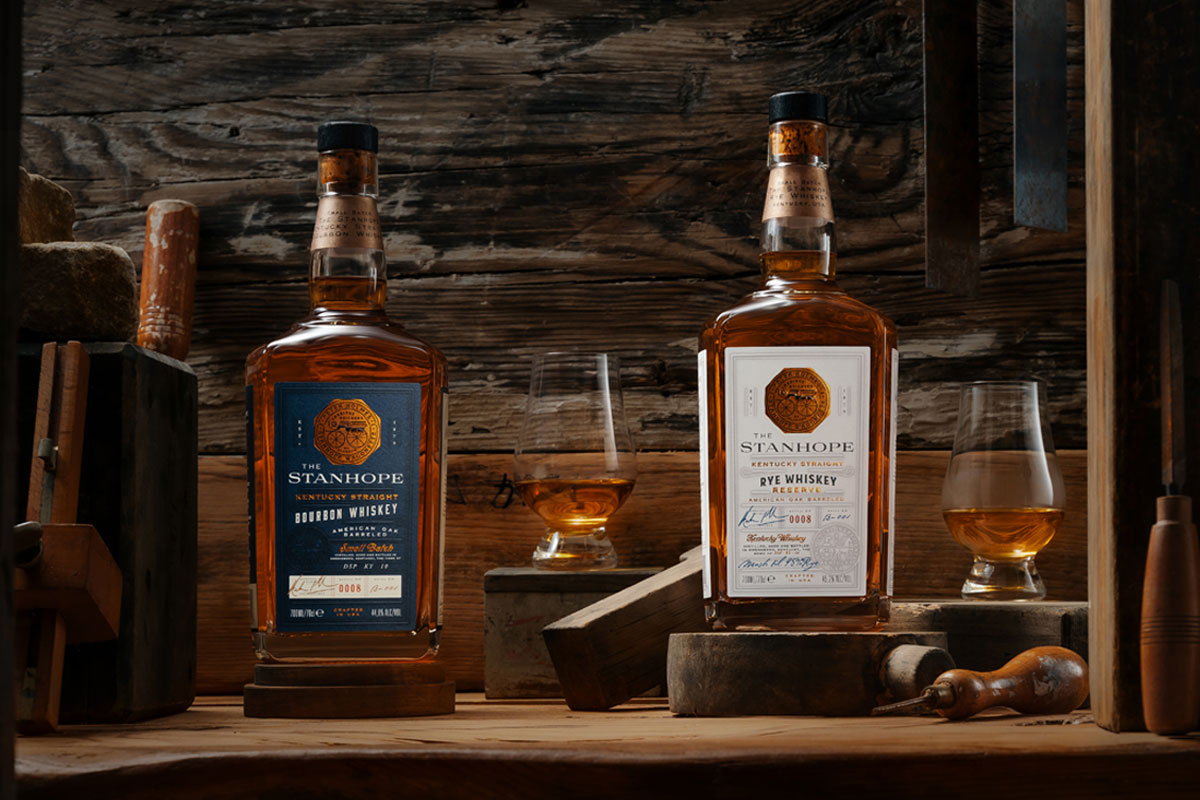 Bottles of Stanhope Kentucky Whiskey Bourbon and Rye Whiskey stands on a wooden table with nosing glasses containing the whiskies.