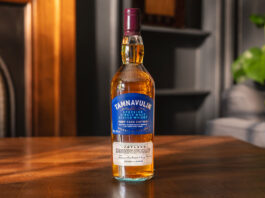 A bottle of Tamnavulin Port Cask Edition sits on a wooden table in a living room.