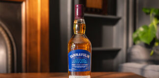 A bottle of Tamnavulin Port Cask Edition sits on a wooden table in a living room.