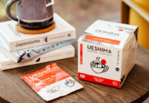 Ueshima Coffee Company Pour Over Coffee Bags box with a sachet of the coffee bag next to it with a pile of books on a wooden table.