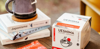 Ueshima Coffee Company Pour Over Coffee Bags box with a sachet of the coffee bag next to it with a pile of books on a wooden table.