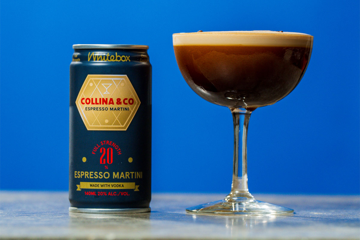 A can of Whitebox Cocktails' Collina & Co Espresso Martini serve stands next to a coupe glass with the cocktail inside, both stand on a tabletop against a blue background.