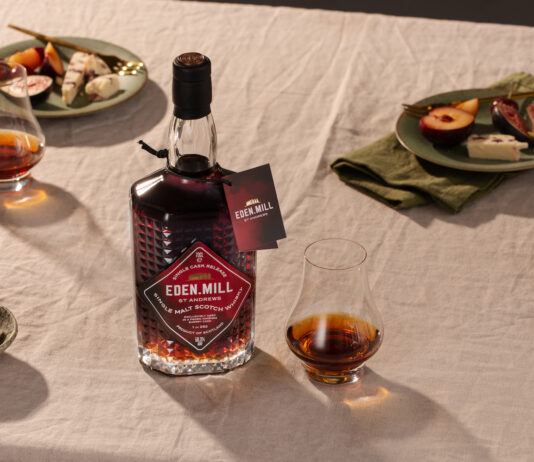 Eden Mill launches rare PX cask bottling A bottle with Eden Mill Pedro Ximénez Single Cask sits on a table with food on plates and a nosing glass with a sample of the whisky inside.