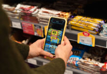 A person holds a phone with Jisp app open on it to scan a product on a store shelf.