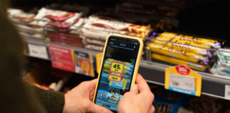 A person holds a phone with Jisp app open on it to scan a product on a store shelf.