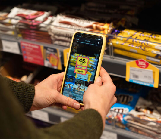 Jisp trials in-store NPD service A person holds a phone with Jisp app open on it to scan a product on a store shelf.