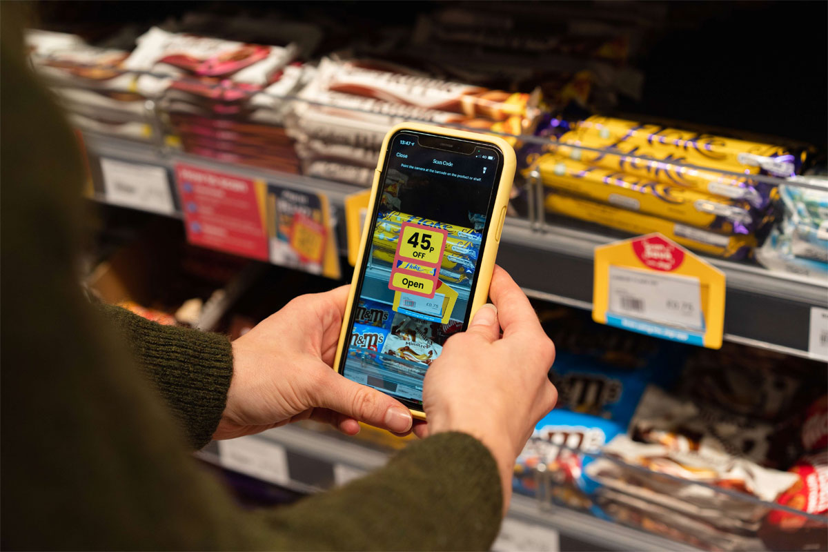 A person holds a phone with Jisp app open on it to scan a product on a store shelf.