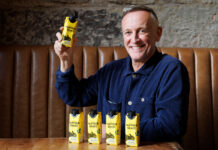 Paul Crawford, founder of Panther M*lk sits in a booth with cartons of Panther Shake whilst holding one.