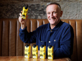 Panther M*lk eyes up European expansion Paul Crawford, founder of Panther M*lk sits in a booth with cartons of Panther Shake whilst holding one.