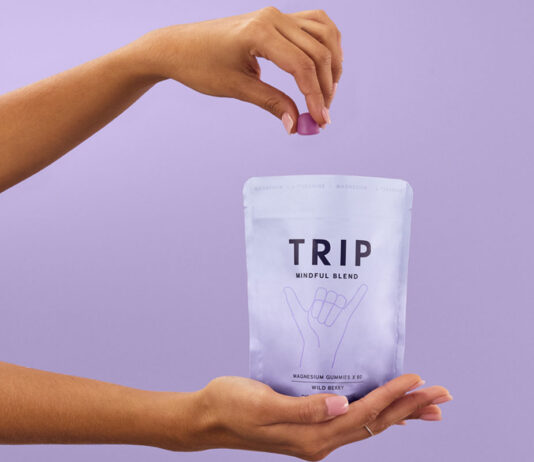 TRIP expands into the gummies market A person holds a bag of TRIP Magnesium Gummies and takes a few out with their other hand against a lilac purple background.