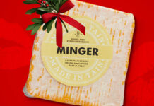 A packet of Aldi Minger Cheese is set against a red background with a sprig of Mistletoe on top of it.