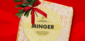 A packet of Aldi Minger Cheese is set against a red background with a sprig of Mistletoe on top of it.