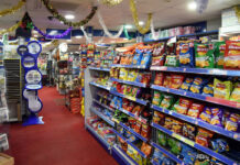 A shop floor with crisps on the shelves to the right and tinsel hanging from the roof.