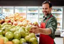 A man is stocking apples in a grocery store.