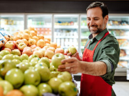 GroceryAid builds staff support for Christmas A man is stocking apples in a grocery store.