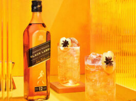 Diageo celebrates a Royal Five A bottle of Johnnie Walker Black Label is next to two cocktail serves set against an orange and yellow background.