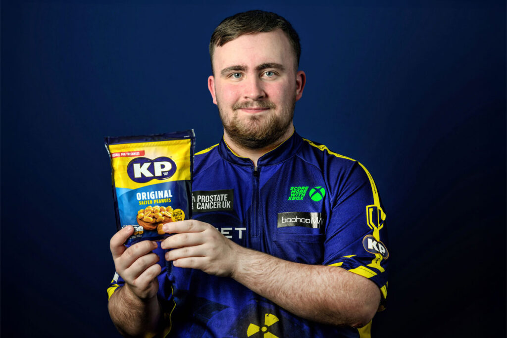 Darts star Luke Littler holds a pack of KP Nuts Original Salted Peanuts.