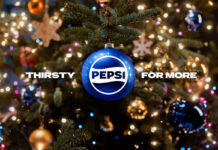 A Christmas tree with a blue bauble hanging from its branch with the Pepsi logo on it and surrounding text that reads "Thirsty For More".