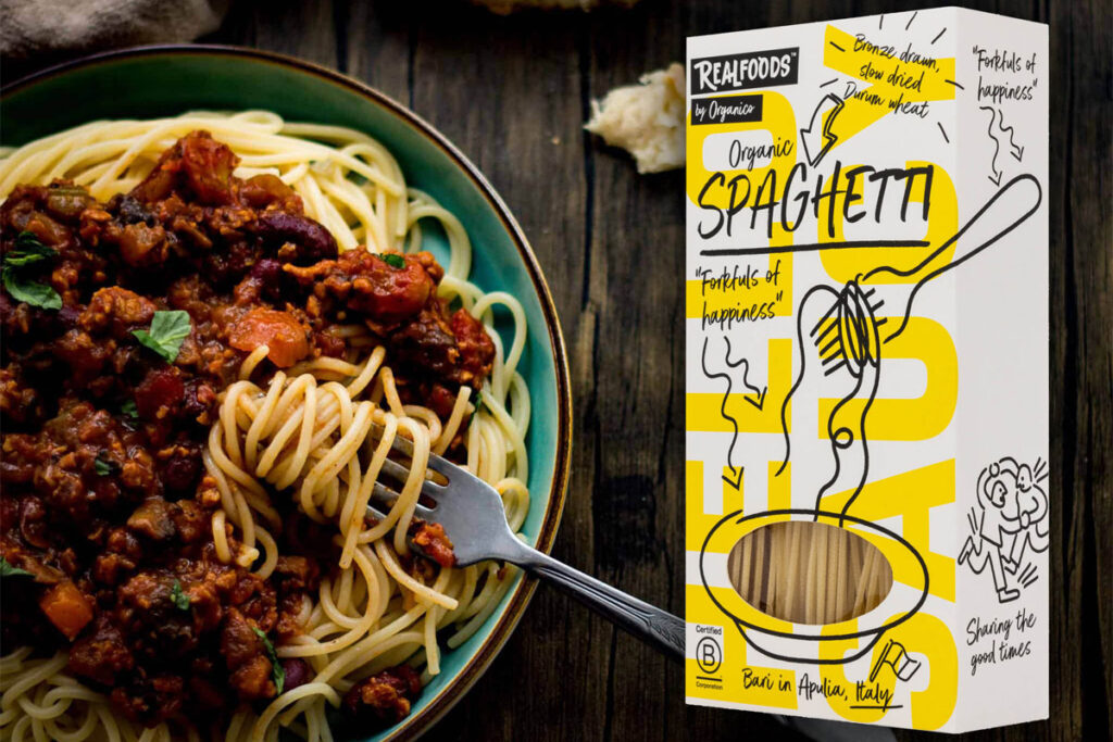 A packet of Realfoods by Oraganico Organic Spaghetti is placed on top of an image of a bowl of spaghetti bolognese.